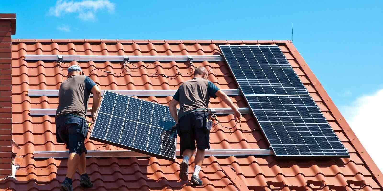 Roofer installing a solar panel on a roof.